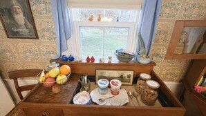 A kitchen counter with a fruit bowl, jars, and a window with a view of the garden.