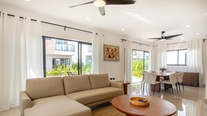 A modern living room with a sofa, a round coffee table, and a dining area with chairs and a table. - Three-bedroom villa with private pool (Punta Cana)
