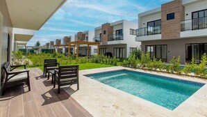 A modern residential complex with a swimming pool, outdoor seating, and a well-maintained garden. - Three-bedroom villa with private pool (Punta Cana)