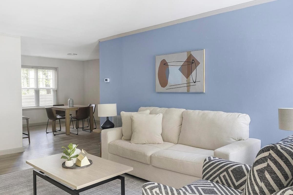 Una sala de estar con sofá, sillones, una mesa de centro y un comedor con mesa y sillas.