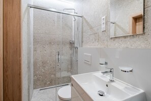 A modern bathroom with a glass-enclosed shower, a white sink, and a toilet. - Blueground | Nusle, balcony, quiet, nr Vysehrad (PRG-64) (Prague)