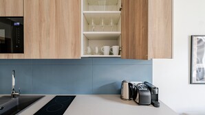 Ett modernt kök med inbyggd mikrovågsugn, diskho, induktionshäll och kaffebryggare.