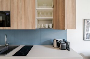 Eine moderne Küche mit integriertem Mikrowellenherd, einer Spüle, einem Induktionskochfeld und einer Kaffeemaschine.