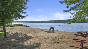 A sandy beach with picnic tables and a tire swing.