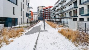 Ein verschneiter Weg zwischen modernen Wohngebäuden mit Balkonen und großen Fenstern.