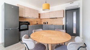 Eine moderne Küche mit einem runden Holztisch, grauen Schränken und einem schwarzen Kühlschrank.