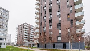 A modern multi-story residential building with balconies, a flat roof, and a paved ground floor. - Blueground | Invalidovna, balcony, nr Vltava (PRG-90) (Prague)