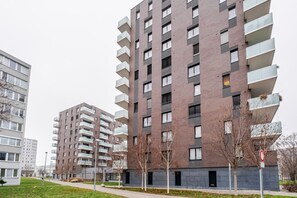 A modern multi-story residential building with balconies, a flat roof, and a paved ground floor. - Blueground | Invalidovna, balcony, nr Vltava (PRG-90) (Prague)