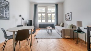 Una sala moderna con comedor, un sofá, una mesa de centro y un televisor.