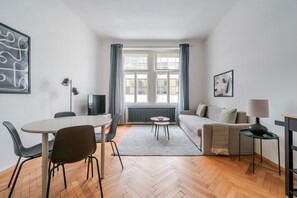 A modern living room with a dining area, a sofa, a coffee table, and a TV. - Blueground | Holešovice, view, nr Vltava (PRG-92) (Prague)