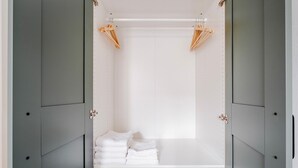 Un vestidor con puertas grises, interior blanco y perchas de madera en el techo.