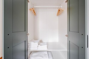 A walk-in closet with grey doors, a white interior, and wooden hangers on the ceiling. - Blueground | Holešovice, view, nr Vltava (PRG-92) (Prague)