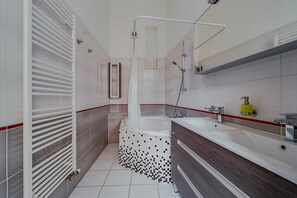 Casa de banho moderna com banheira, chuveiro e lavatório com espelho.