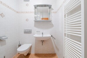 Une salle de bain avec des toilettes, un lavabo et une douche.