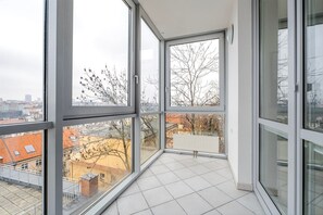 Un apartamento moderno en un edificio alto, con ventanas amplias, piso de baldosas y vista panorámica de la ciudad.