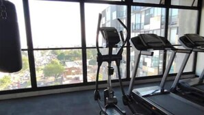 Ein Fitnessstudio mit Trainingsgeräten, großen Fenstern und Blick auf Gebäude.