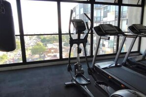 Ein Fitnessstudio mit Trainingsgeräten, großen Fenstern und Blick auf Gebäude.