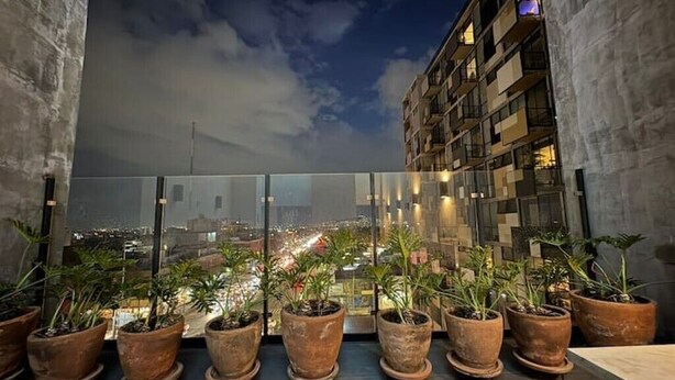Ein Balkon mit Terrakottatöpfen und Blick auf die Stadt bei Nacht.