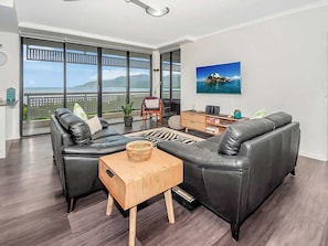 Ein modernes Wohnzimmer mit einer schwarzen Ledersofa, einem Holztisch und einem großen Fenster mit Blick auf das Meer.