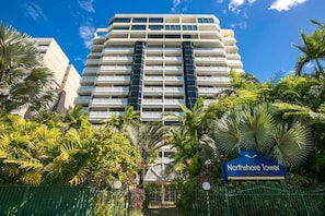 Ein hoch aufragendes Hotel mit modernem Design, umgeben von üppiger Vegetation und Palmen.