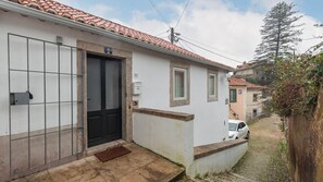 En bostadsbyggnad med ett tak täckt av takpannor, en svart dörr och en liten trädgård framför huset.