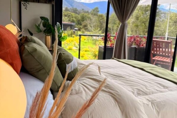 Une chambre avec un grand lit, donnant sur un jardin et dotée d’un balcon avec une balustrade.