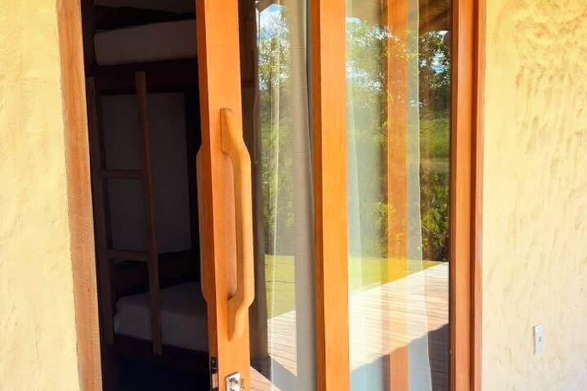 Una puerta de madera con un cartel arriba, que da a una habitación con una cama y una ventana.