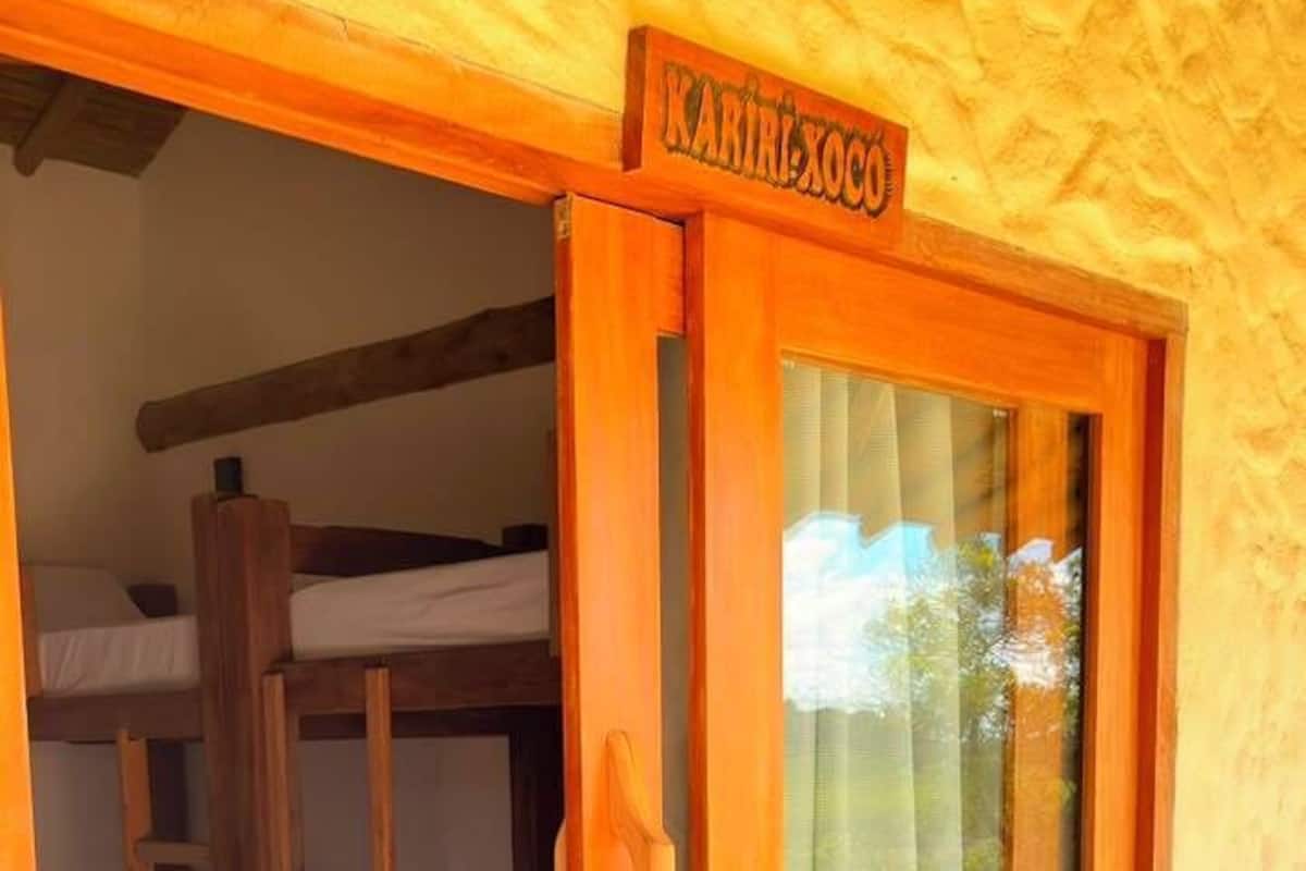 Una puerta de madera con un letrero que dice 'Karibikoco' que da a una habitación con literas.