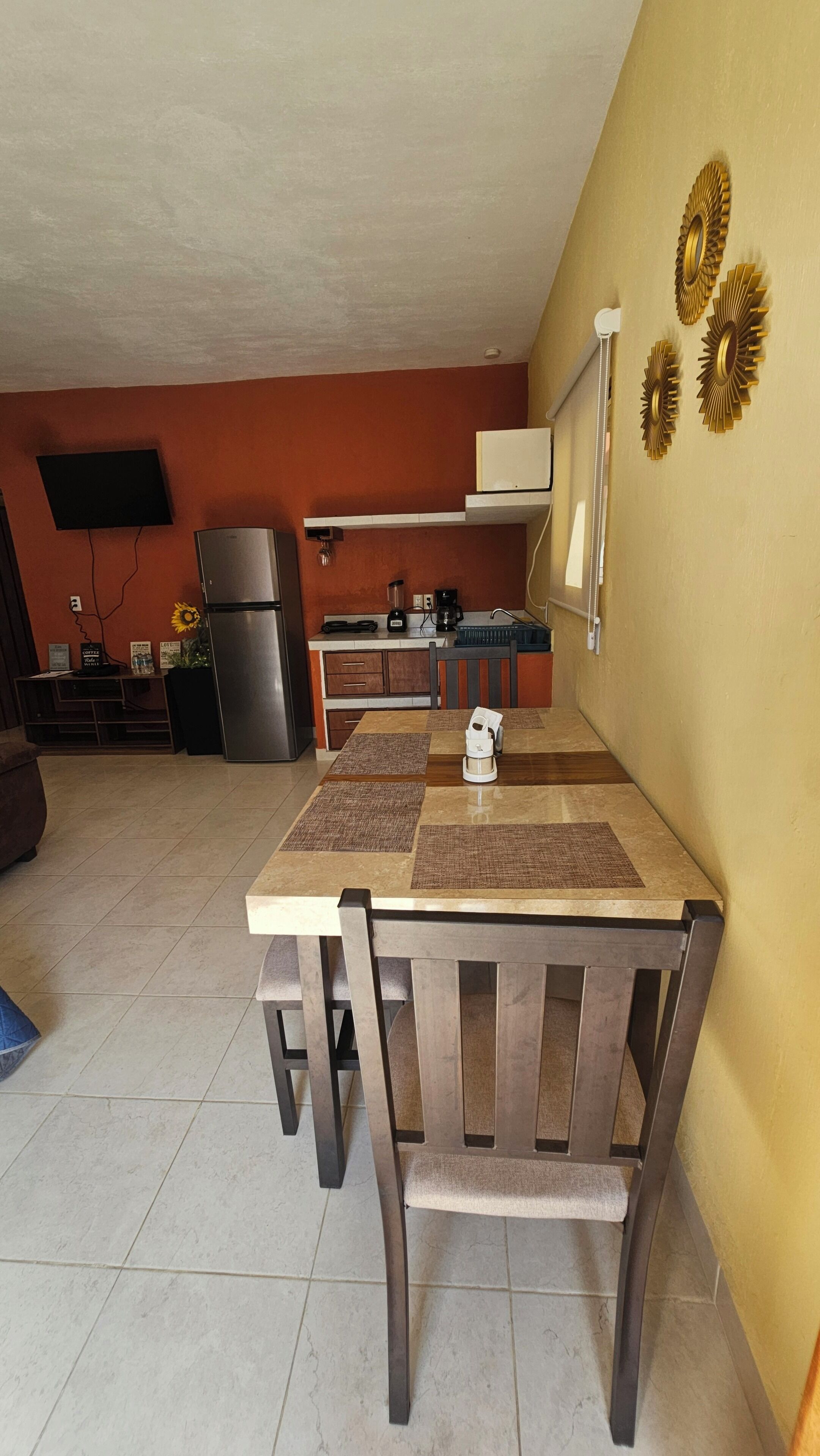 Un comedor con mesa y sillas, una cocina al fondo y decoración en la pared.