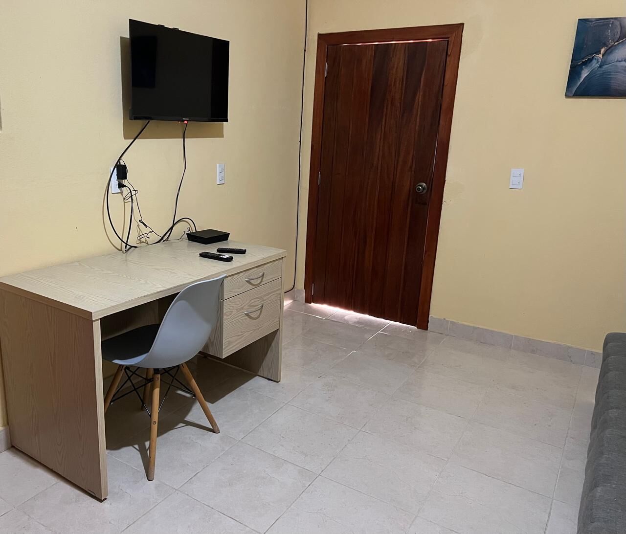 A room with a desk, chair, TV, and a wooden door.