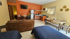 A compact living space with a kitchenette, a sofa, a dining table, and a TV. - Suites el Ángel (Tuxtla Gutiérrez)