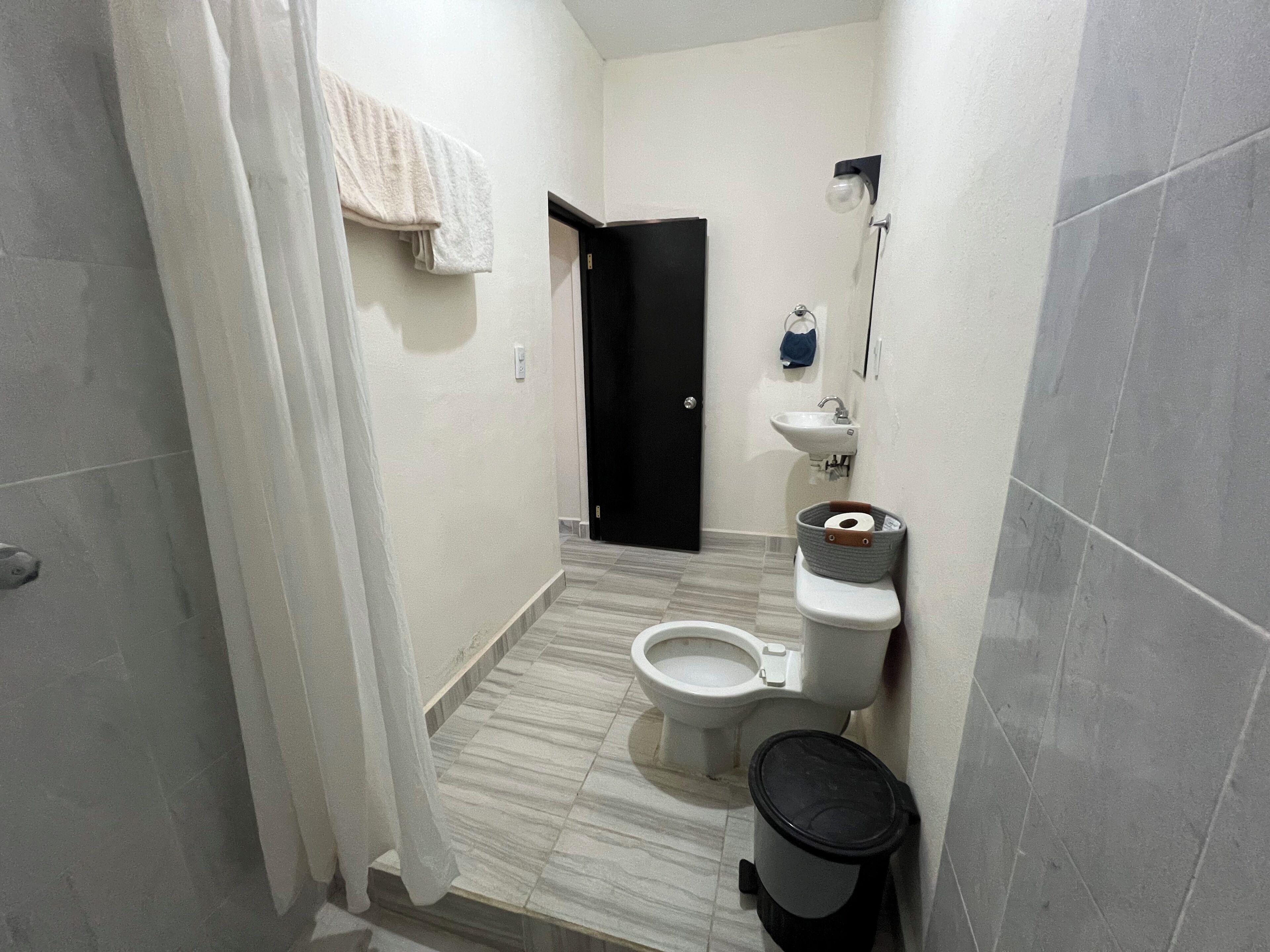 Une petite salle de bain avec des toilettes, un lavabo et une poubelle.