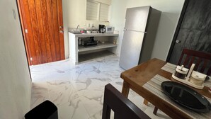 A compact kitchen with a refrigerator, a sink, and a microwave. There is a wooden door and a tiled floor. - Suites el Ángel (Tuxtla Gutiérrez)