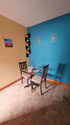 Zona pranzo con tavolo e sedie, una parete blu e una piccola pianta in vaso appesa al muro.