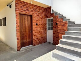 Un edificio residencial con fachada de ladrillo, puerta de madera, puerta de garaje blanca y escalones de hormigón que conducen a la entrada.