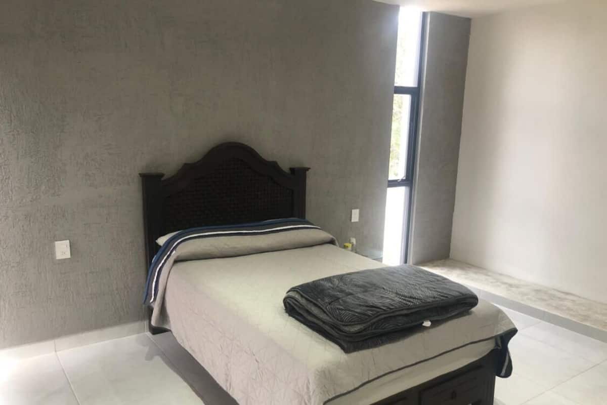 A bedroom with a bed, a window, and a door.