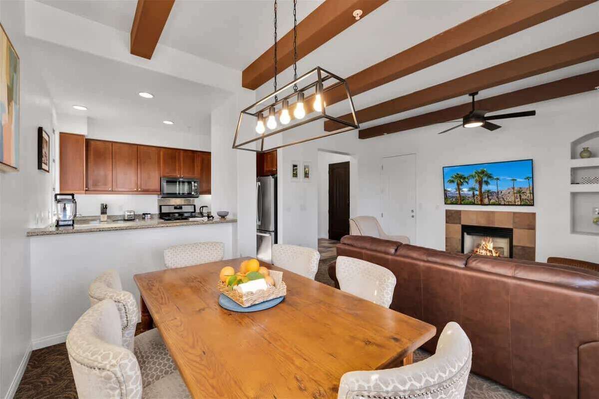 Une cuisine moderne avec des meubles en bois, un coin repas avec une table et des chaises en bois, et un salon avec un canapé en cuir marron.