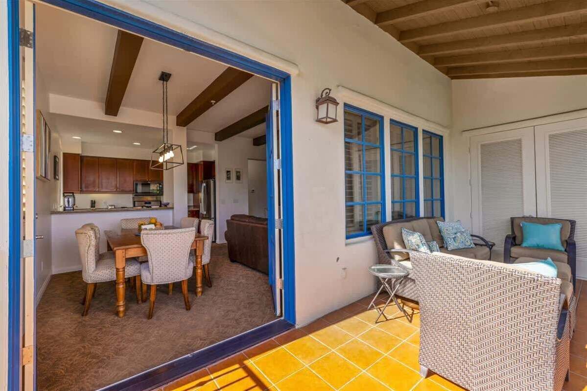 A spacious living area with a dining table and chairs, a sofa, and a small table with a lamp.