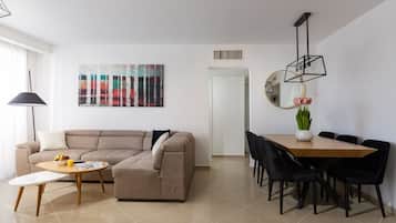A modern living room with a sofa, coffee table, and dining area with chairs.