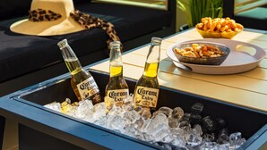 A cozy seating area with a sofa, a coffee table with bottles of Corona Extra beer and snacks, and a view of greenery outside. - Mamad Bright Eilat escape with balcony and pool (Eilat)