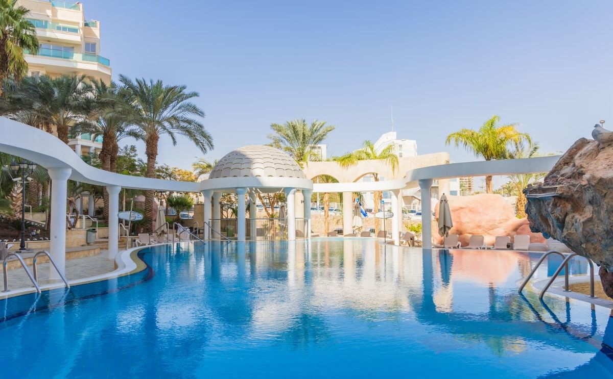 A swimming pool with lounge chairs and a gazebo.