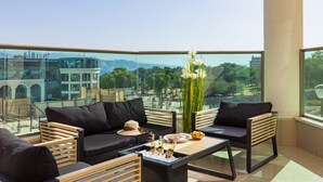 A balcony with a sofa, chairs, a table, and a bottle of beer. - Mamad Bright Eilat escape with balcony and pool (Eilat)