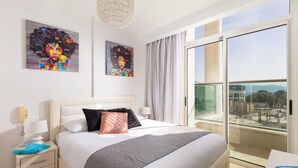 A modern hotel room with a large bed, a bedside table with a lamp, a nightstand, and two artworks on the wall. - Mamad Bright Eilat escape with balcony and pool (Eilat)