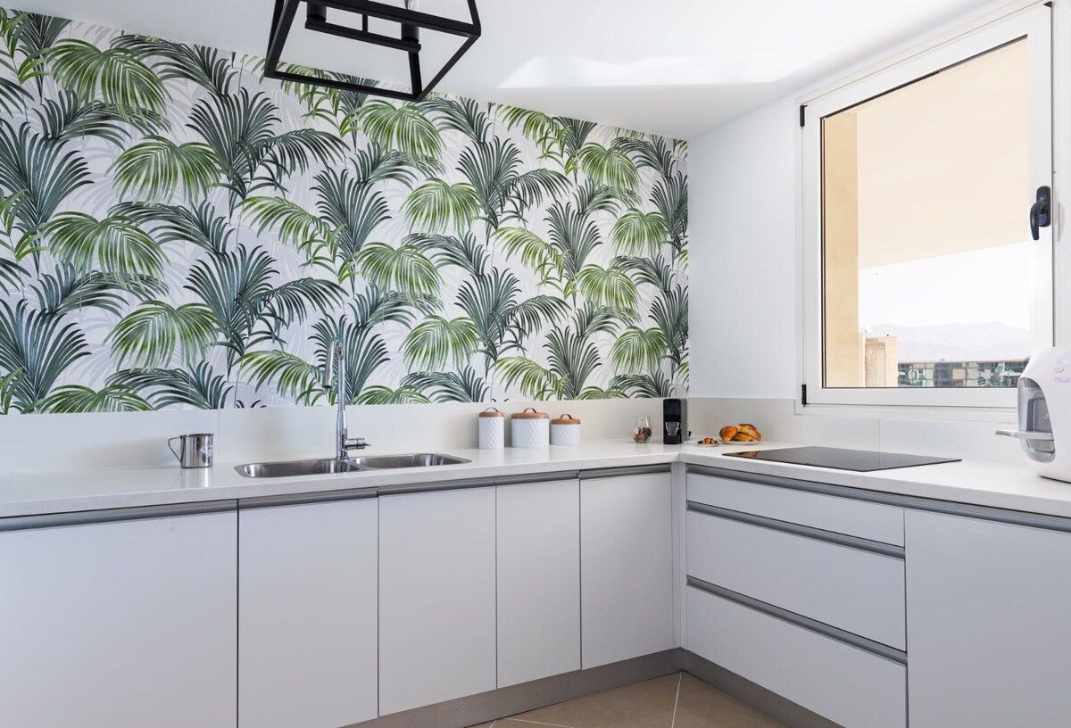 Una cocina moderna con armarios blancos, un lavamanos de acero inoxidable y un ventanal con vistas.