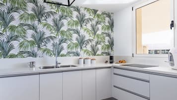 A modern kitchen with white cabinetry, a stainless steel sink, and a window with a view.