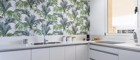 Una cocina moderna con armarios blancos, un lavamanos de acero inoxidable y un ventanal con vistas.