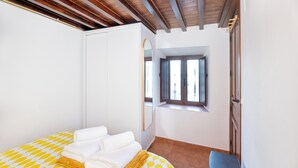 A bedroom with a bed, a window, a wardrobe, and a small desk. - The Crown (1stRight) (Granada)