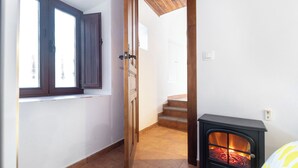 A room with a wooden door, a window, and a black wood-burning stove. - The Crown (1stRight) (Granada)