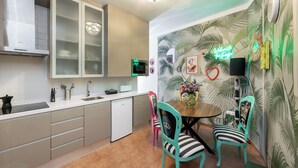 A modern kitchen with a microwave, sink, and cabinets. There is a dining area with a table and chairs. - The Crown (1stRight) (Granada)