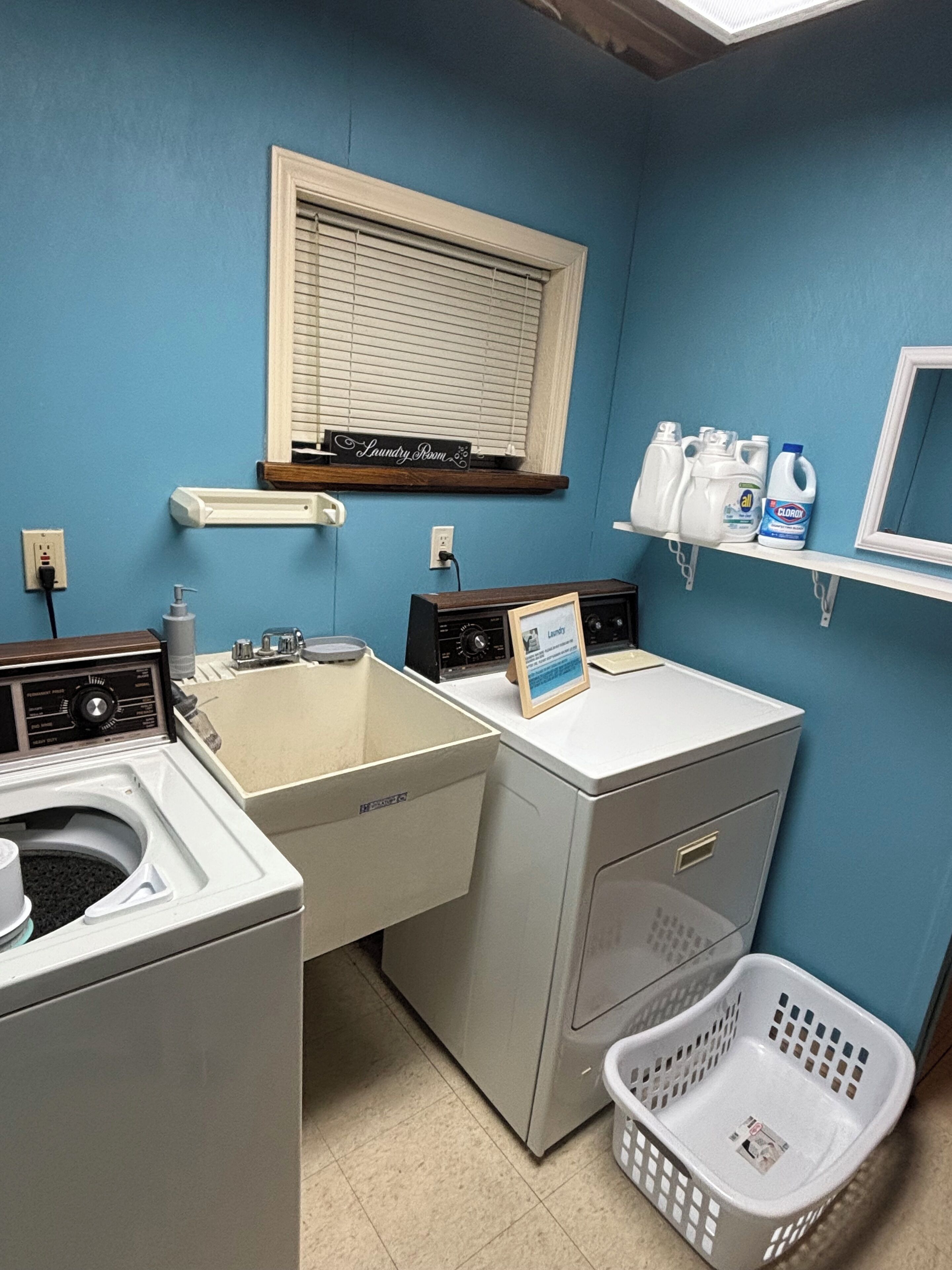 A laundry room with a washing machine, dryer, and a shelf with cleaning supplies.